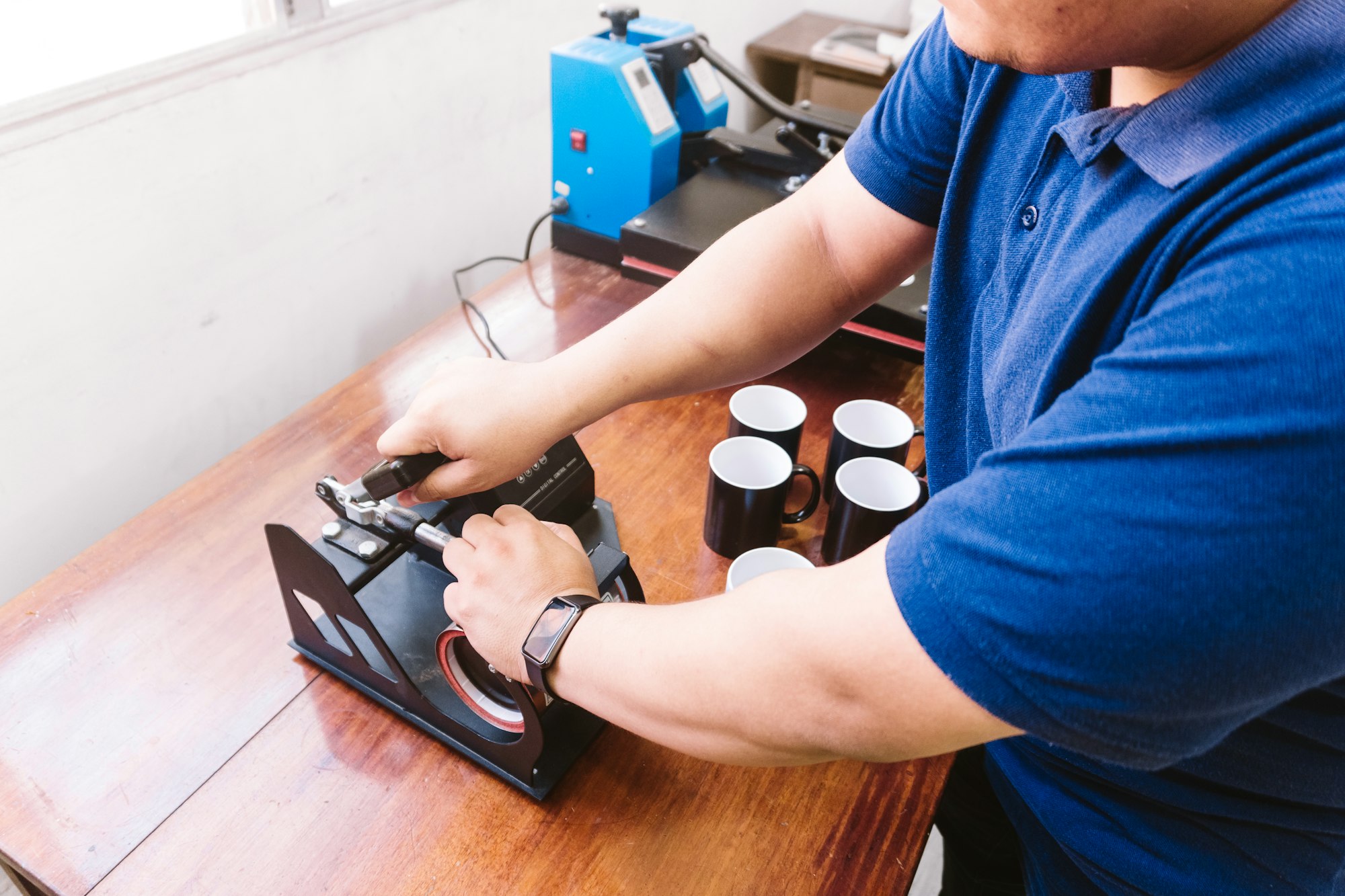 Male working on the printing machine for cups